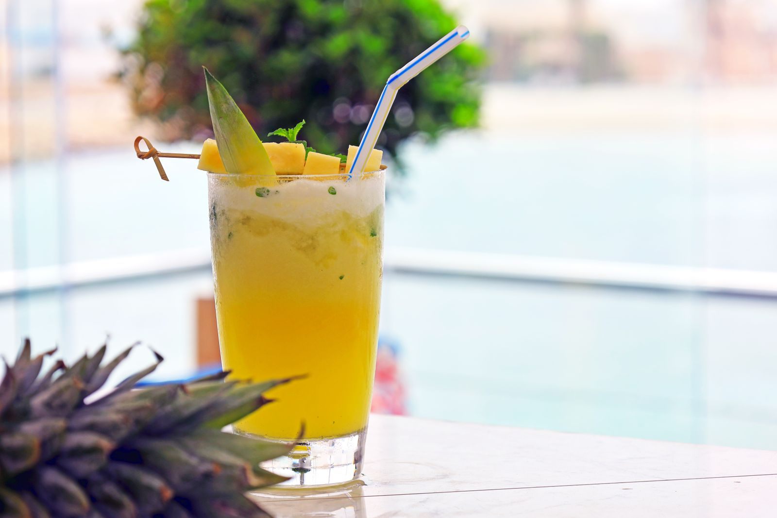Pineapple cocktail by a sunny sea railing, the kind of drink included in free drinks cruise deals
