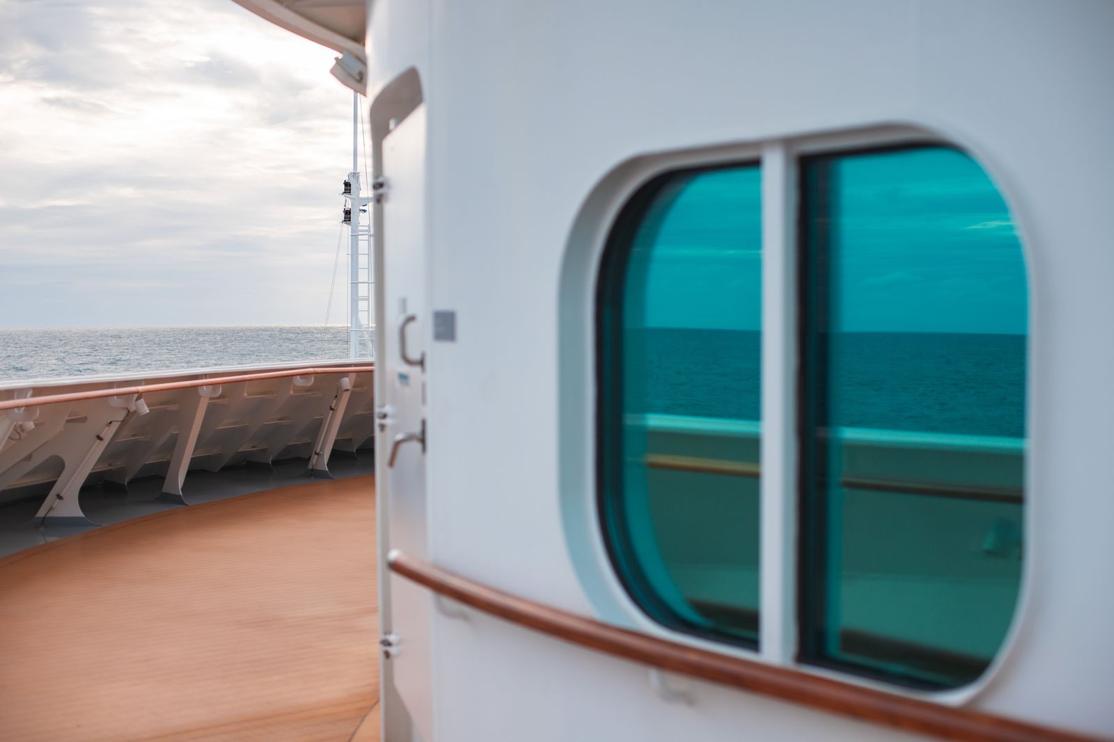 Cruise ship promenade deck and a cabin window reflecting the sea