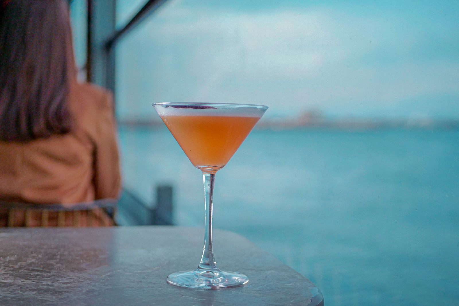 Cocktail on a table overlooking the sea, one of the free cruise perks people look for